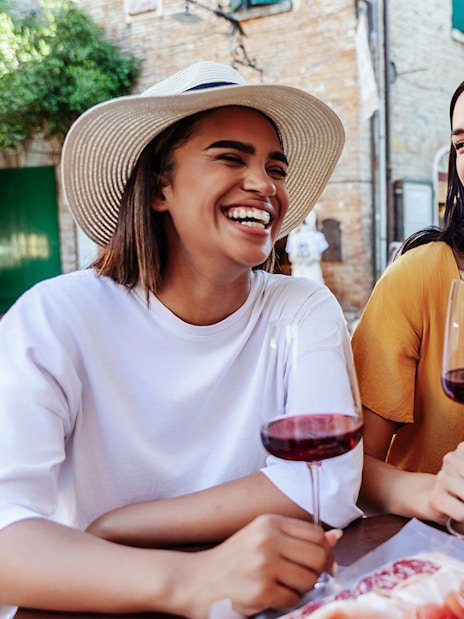 Friends enjoying wine at an outdoor café in a European village.