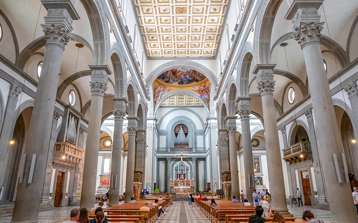 Interior of a grand cathedral in Florence with ornate columns and a decorated ceiling.