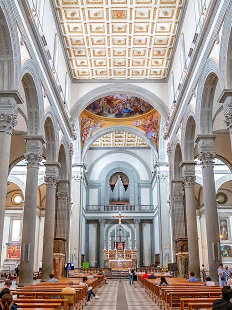 Interior of a grand cathedral in Florence with ornate columns and a decorated ceiling.