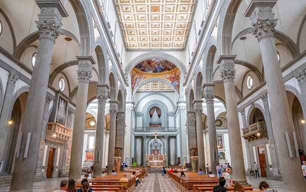 Interior of a grand cathedral in Florence with ornate columns and a decorated ceiling.