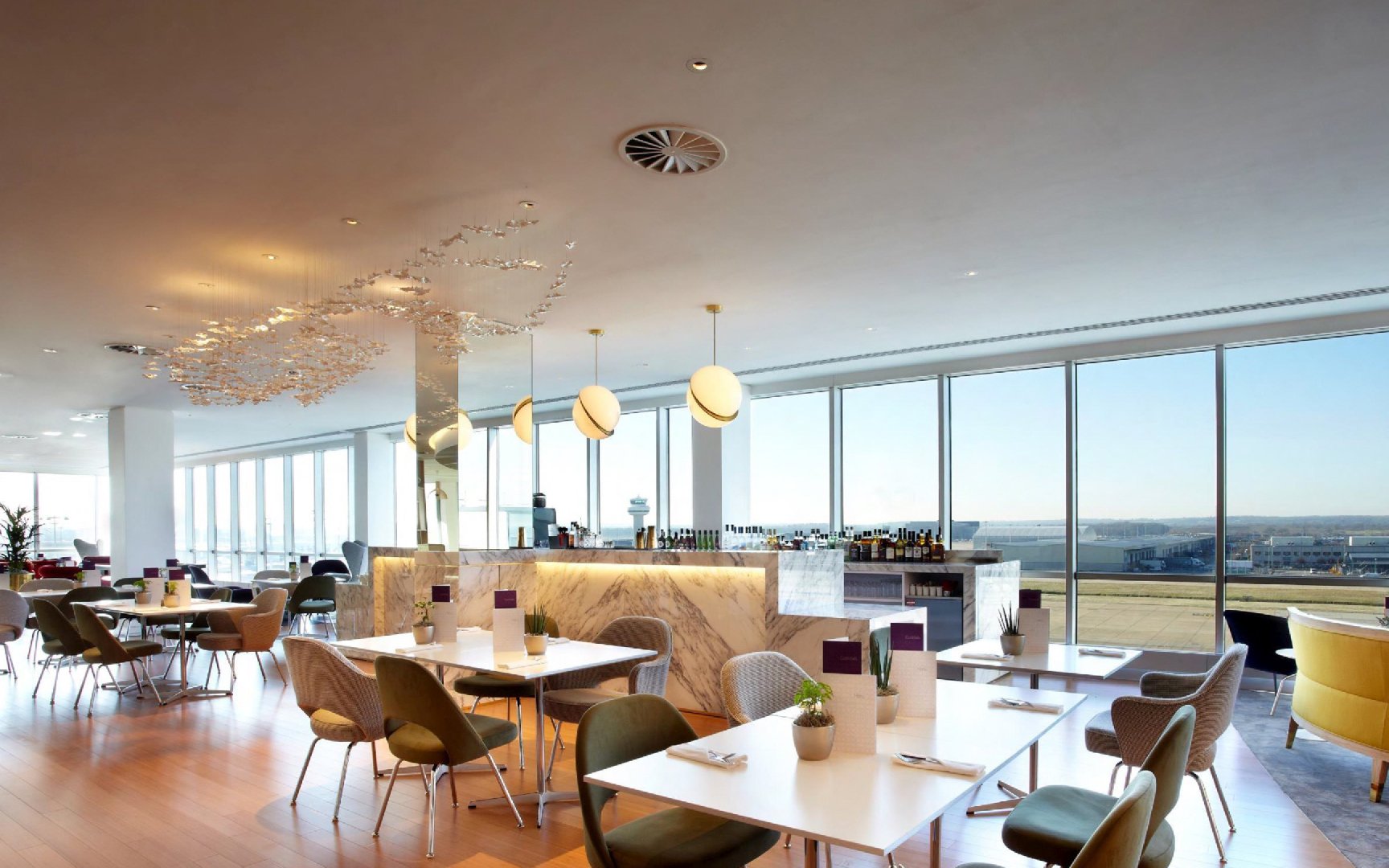 Plaza Premium Lounge seating area with tables and chairs, North Terminal, London Gatwick Airport.