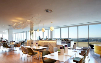 Plaza Premium Lounge seating area with tables and chairs, North Terminal, London Gatwick Airport.