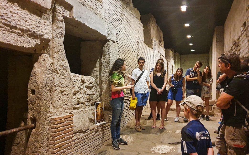 Tour group exploring underground ruins in Naples with a guide explaining historical details.