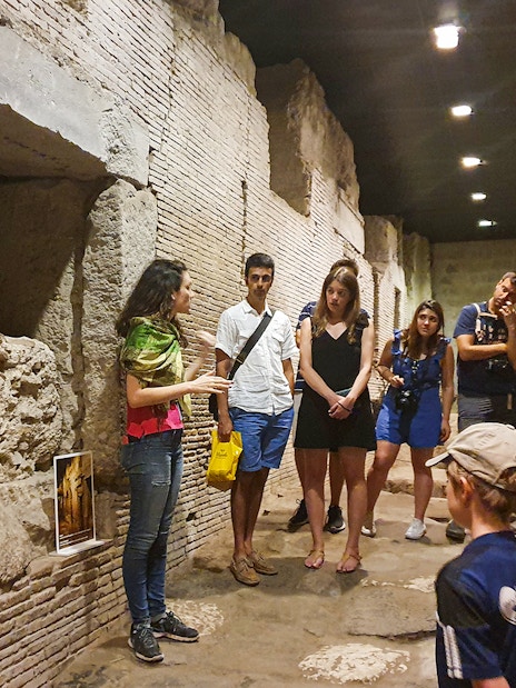 Tour group exploring underground ruins in Naples with a guide explaining historical details.