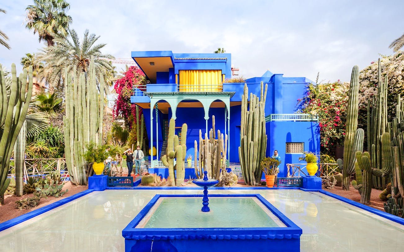 Jardin Majorelle's vibrant blue villa surrounded by cacti and palm trees in Marrakech.