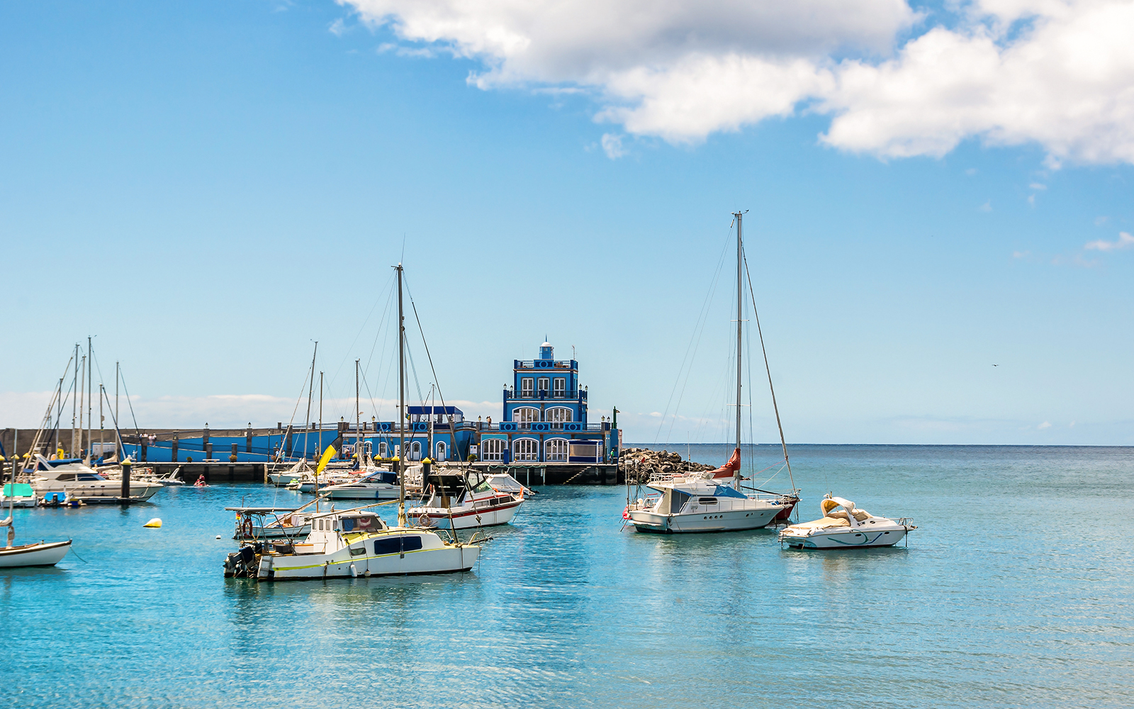 Boats in Marina del Sur with blue harbormaster house, Las Galletas, Tenerife, Spain.