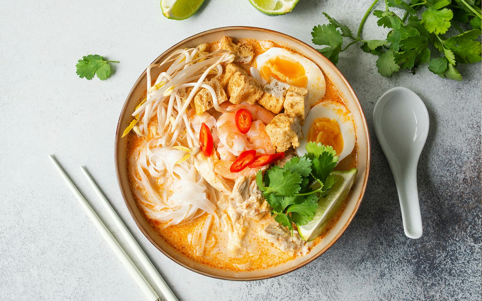 Singapore street food stall serving laksa with vibrant decorations in December.
