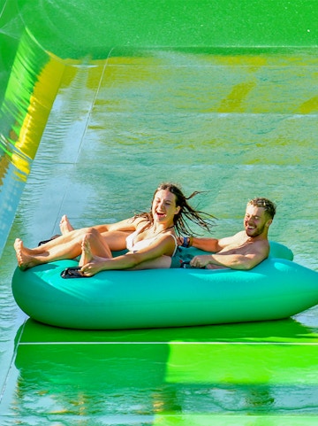 Visitors enjoying a water slide at WaterBom Bali theme park.