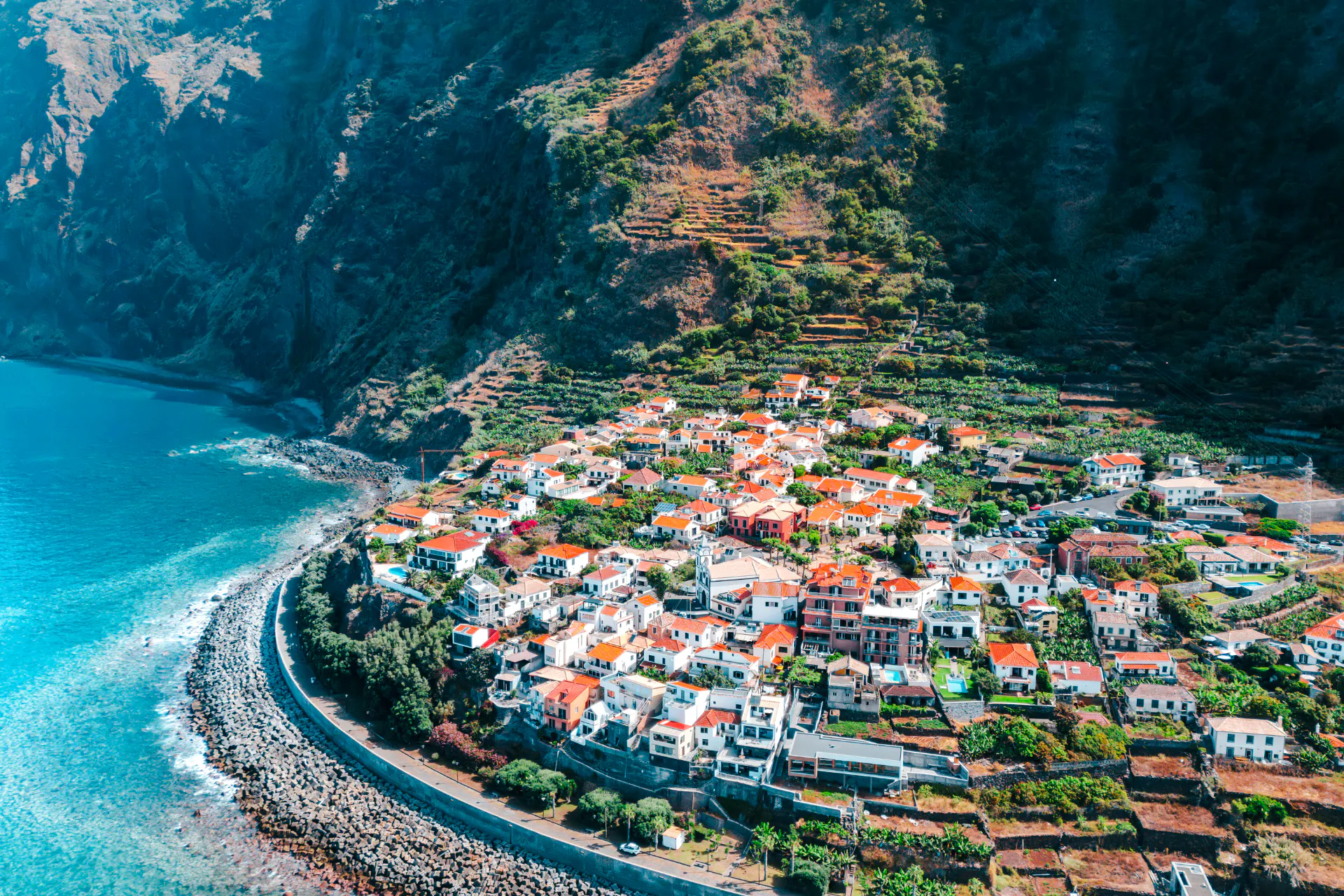Aerial view of coastal village with terraced hills in Madeira, Portugal.