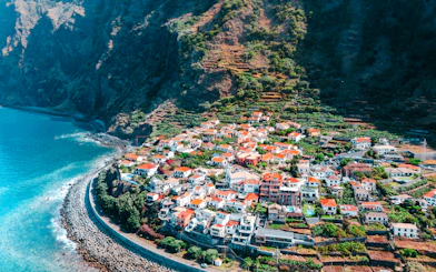 Aerial view of coastal village with terraced hills in Madeira, Portugal.
