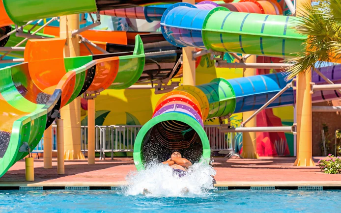 Person exiting colorful water slide at Agadir Aqua Park.