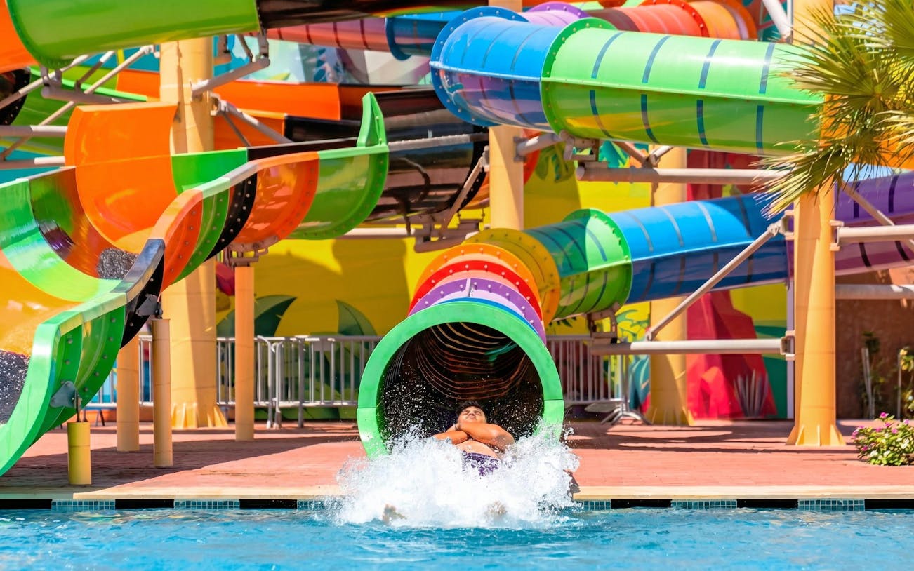 Person exiting colorful water slide at Agadir Aqua Park.