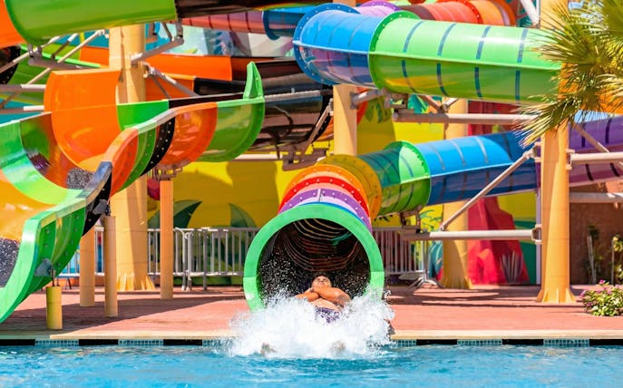 Person exiting colorful water slide at Agadir Aqua Park.