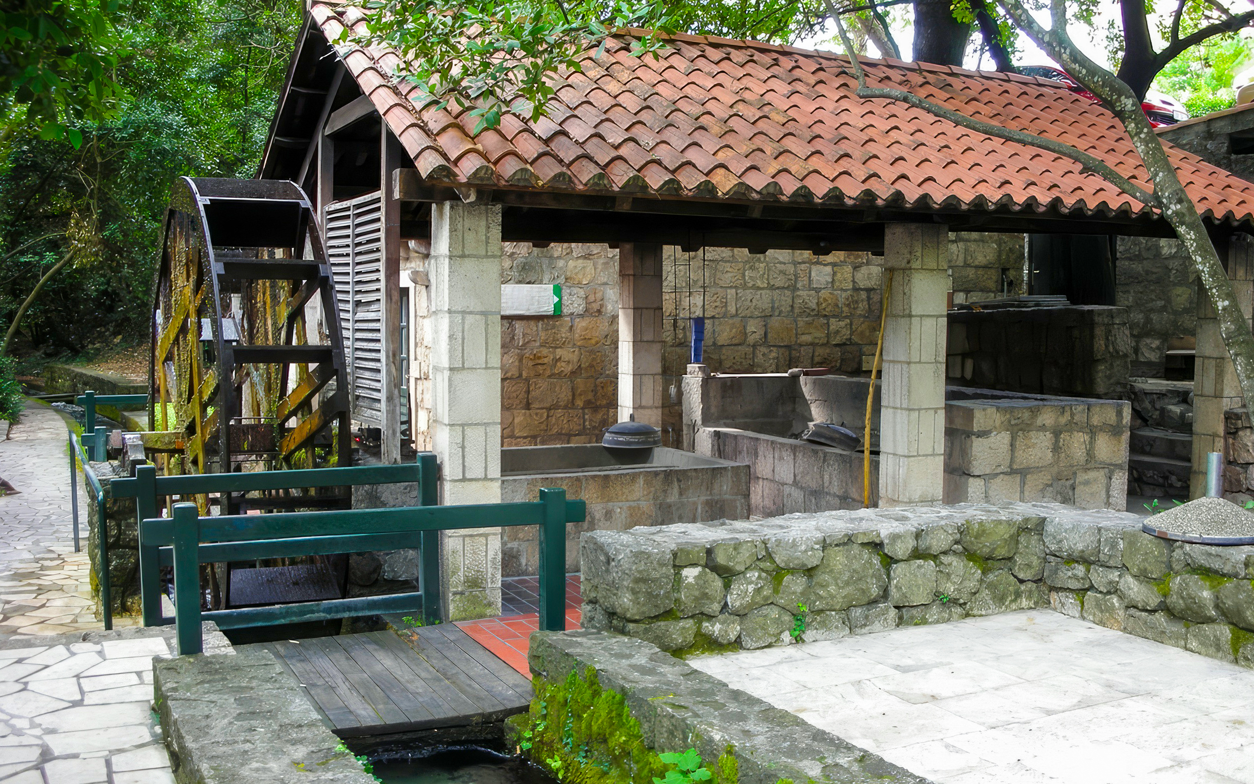 Stone mill with waterwheel in Konavle, Croatia, surrounded by lush greenery.