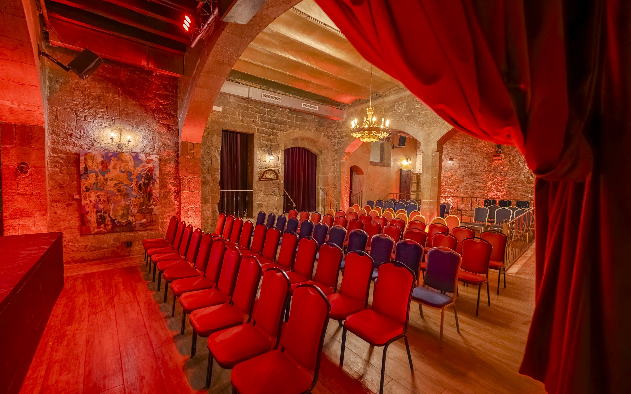 Palau Dalmases Flamenco Show venue with red chairs and stone walls.