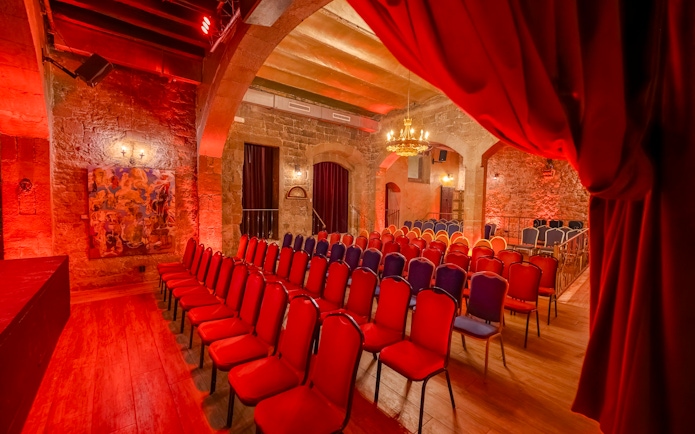 Palau Dalmases Flamenco Show venue with red chairs and stone walls.