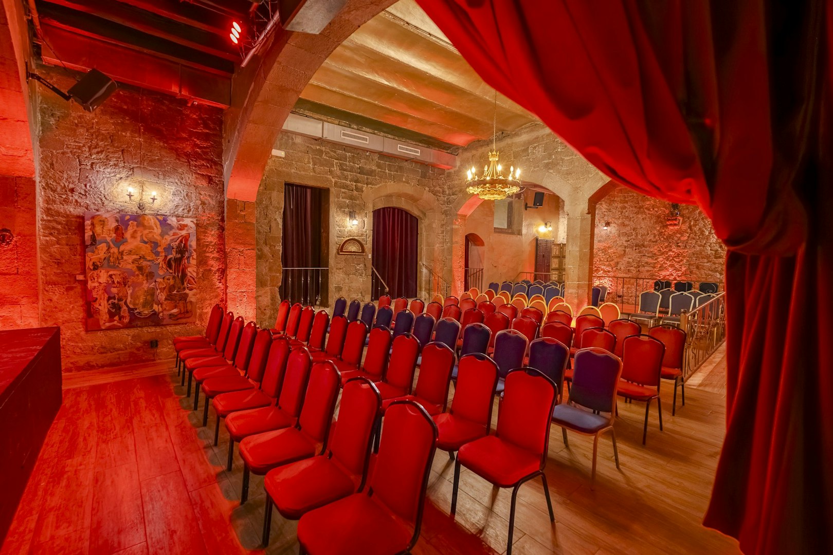 Palau Dalmases Flamenco Show venue with red chairs and stone walls.