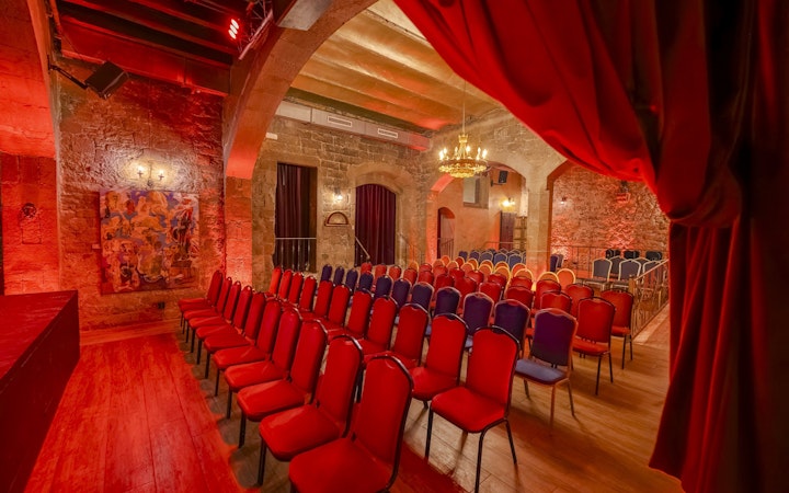 Palau Dalmases Flamenco Show venue with red chairs and stone walls.