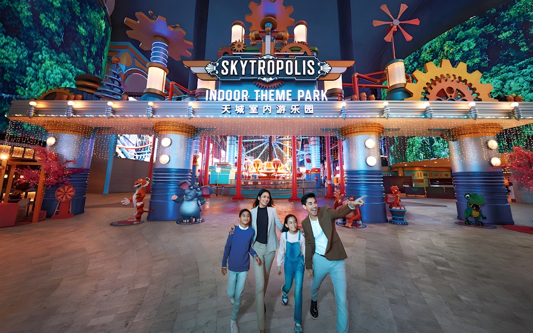 Family enjoying Genting Skytropolis Indoor Theme Park entrance with colorful lights.