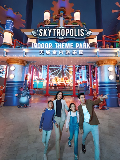 Family enjoying Genting Skytropolis Indoor Theme Park entrance with colorful lights.