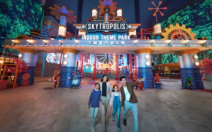 Family enjoying Genting Skytropolis Indoor Theme Park entrance with colorful lights.