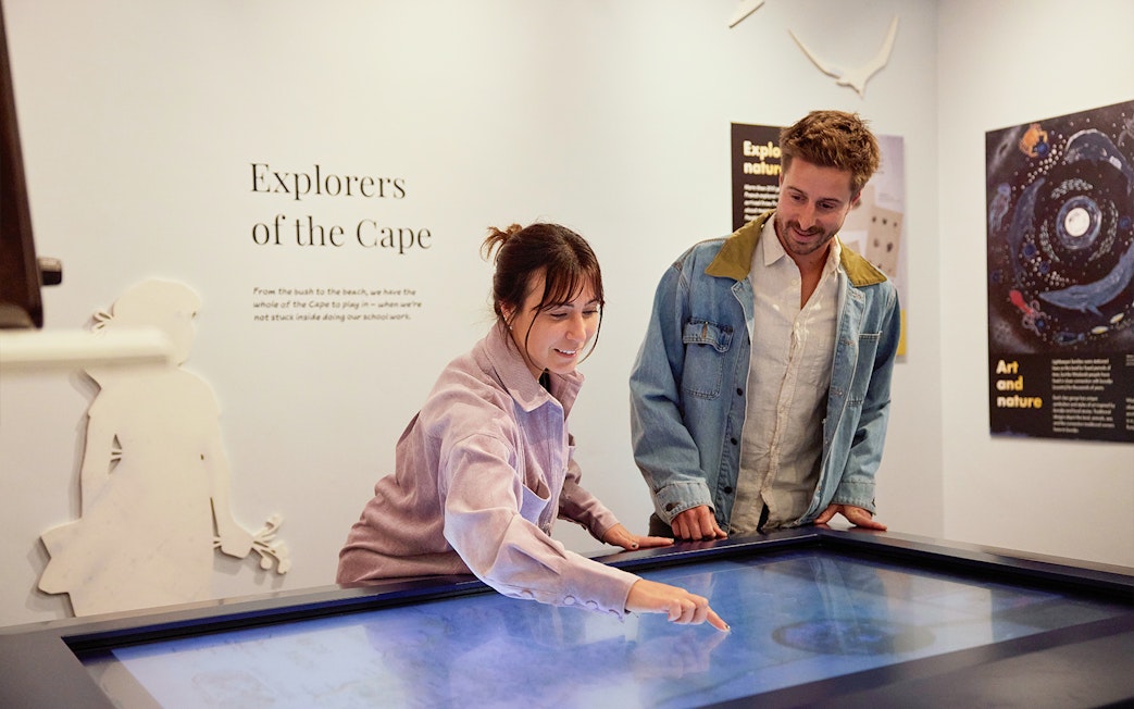Visitors interact with "Explorers of the Cape" display at lighthouse museum.