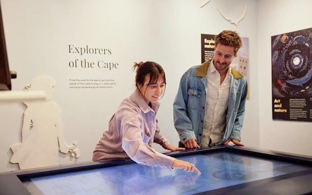Visitors interact with "Explorers of the Cape" display at lighthouse museum.
