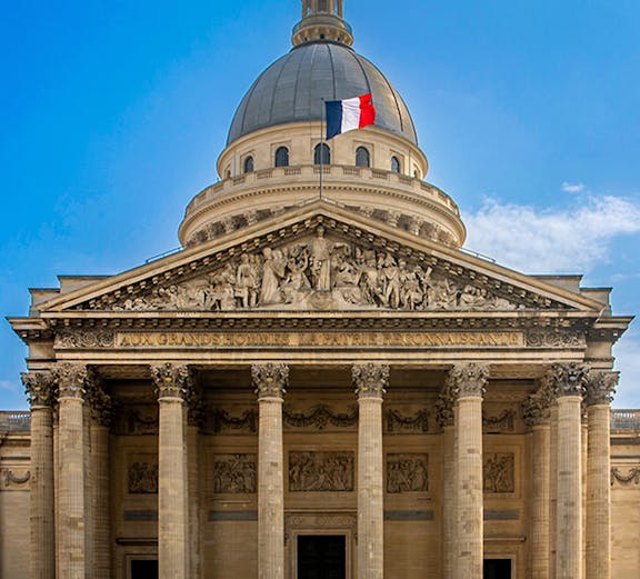 Pantheon in Paris with French flag atop the dome, showcasing neoclassical architecture.