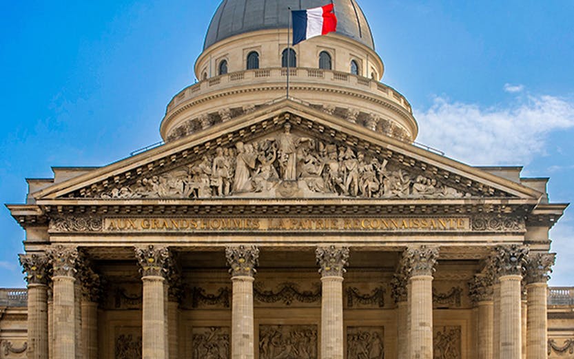 Pantheon in Paris with French flag atop the dome, showcasing neoclassical architecture.