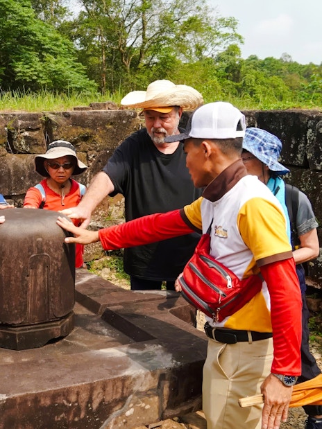Tour group exploring ancient artifact at My Son Sanctuary, Vietnam.