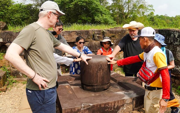 Tour group exploring ancient artifact at My Son Sanctuary, Vietnam.