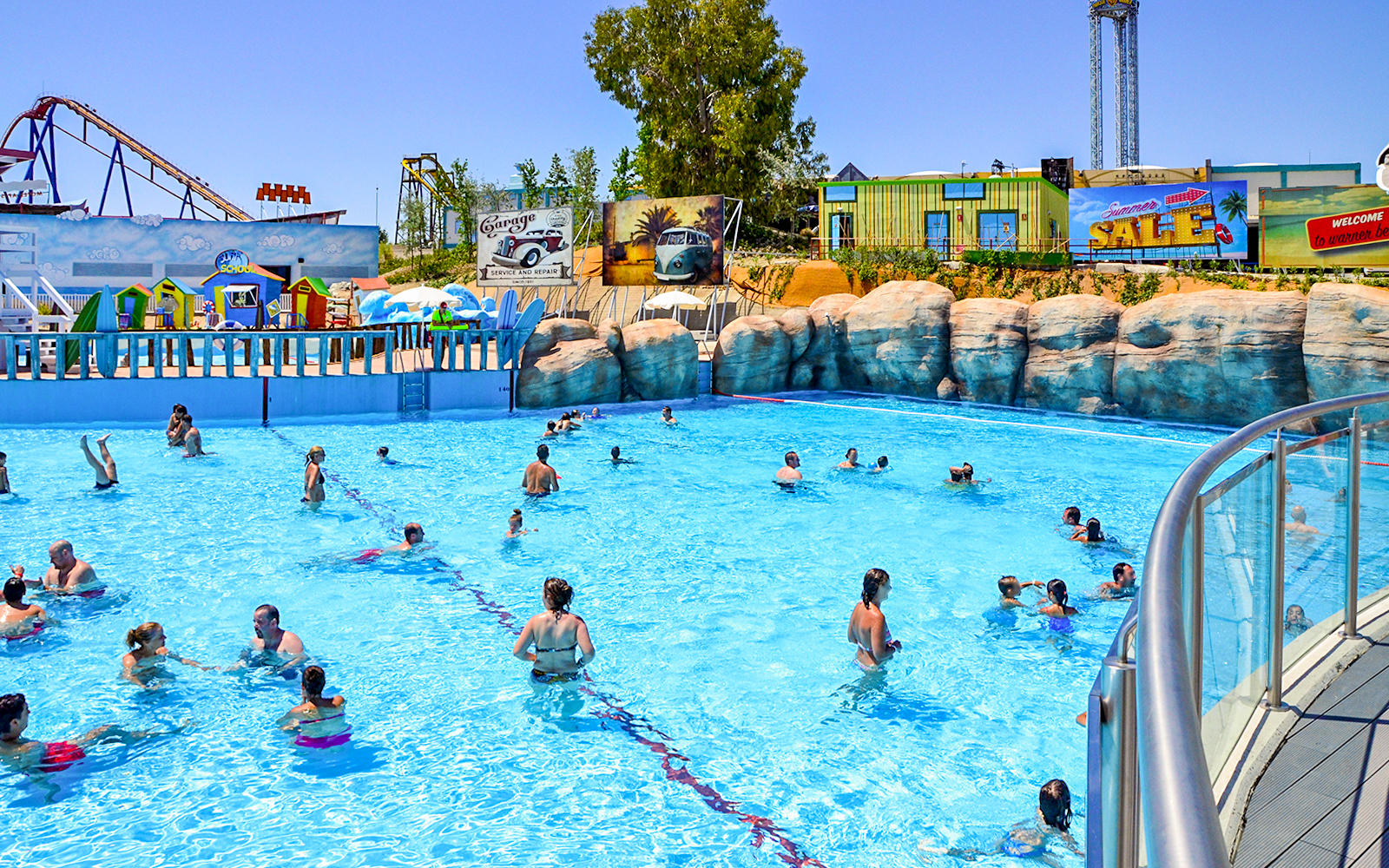 Visitors enjoying the wave pool at Parque Warner Beach, Madrid with roller coasters in the background.