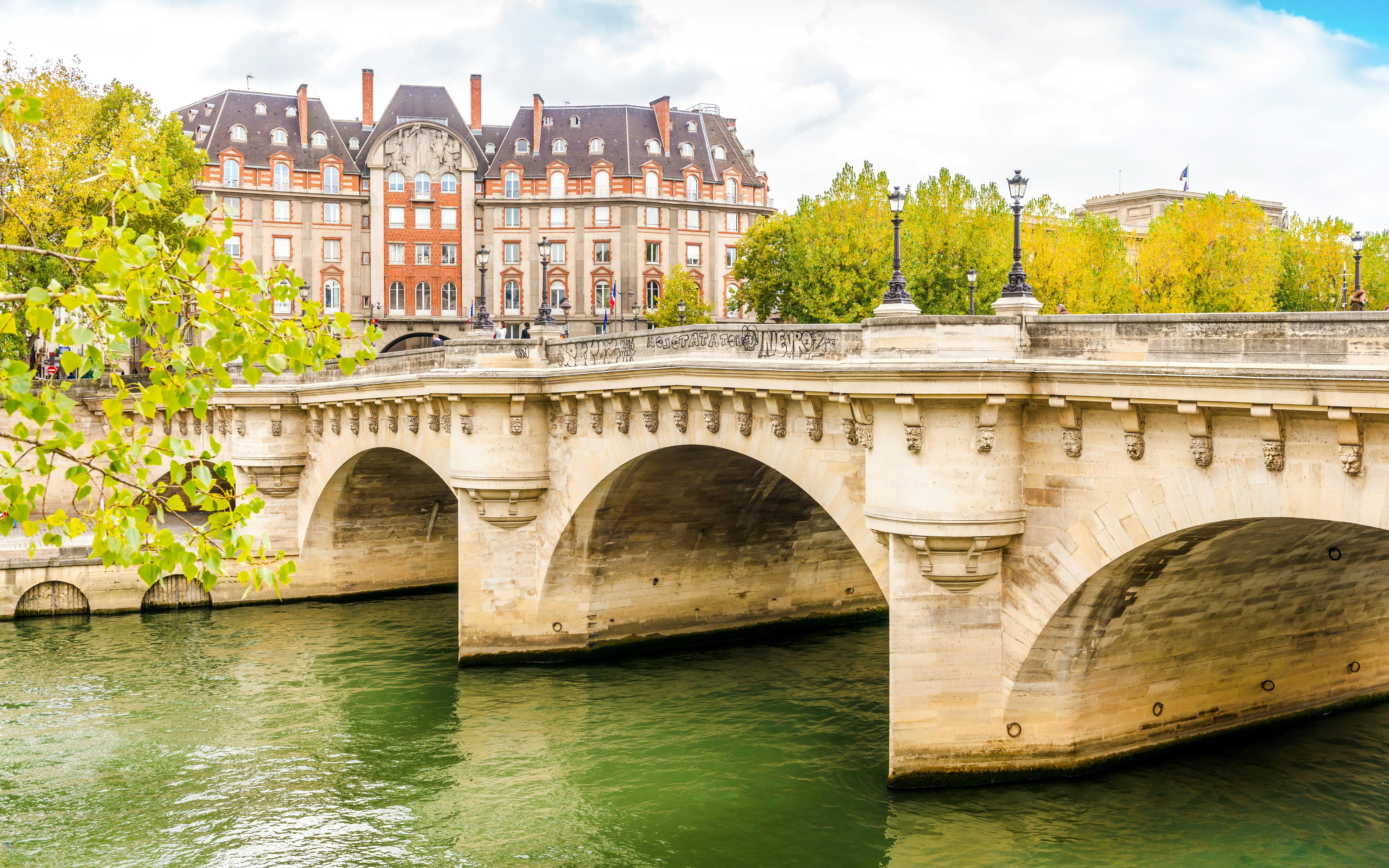 Pont Neuf bridge over the Seine River in Paris with historic buildings in the background.