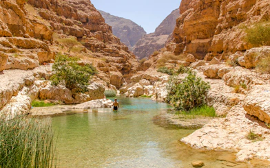 Wadi Shab in Tiwi, Oman with vertical cliffs and clear green water.