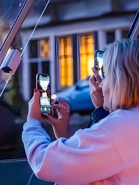 People taking photos through a boat window during the Happy Holidays Evening Cruise.