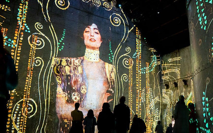 Visitors viewing immersive art projections at Fabrique des Lumières.