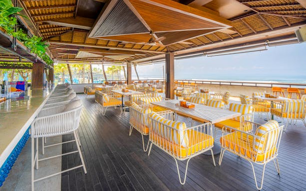 Outdoor seating area at Atlas Beach Club with ocean view and striped chairs.
