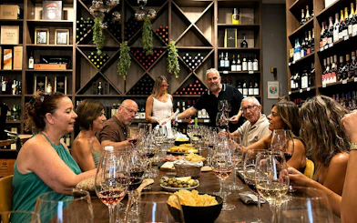 Group enjoying wine tasting with tapas in Málaga wine cellar.