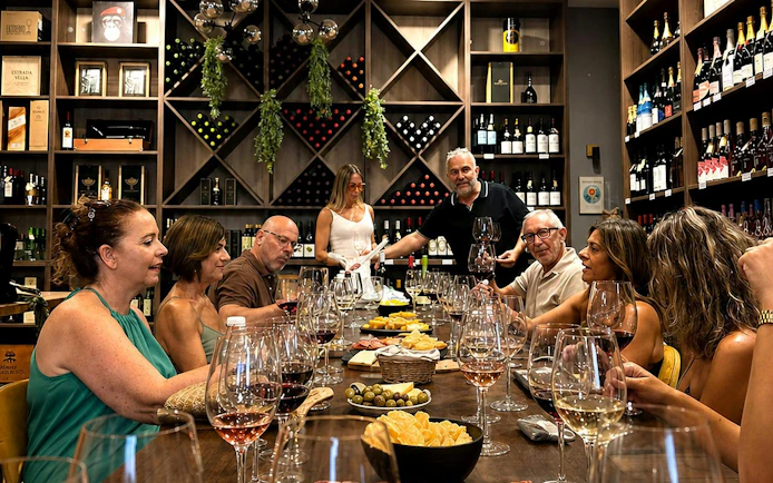 Group enjoying wine tasting with tapas in Málaga wine cellar.