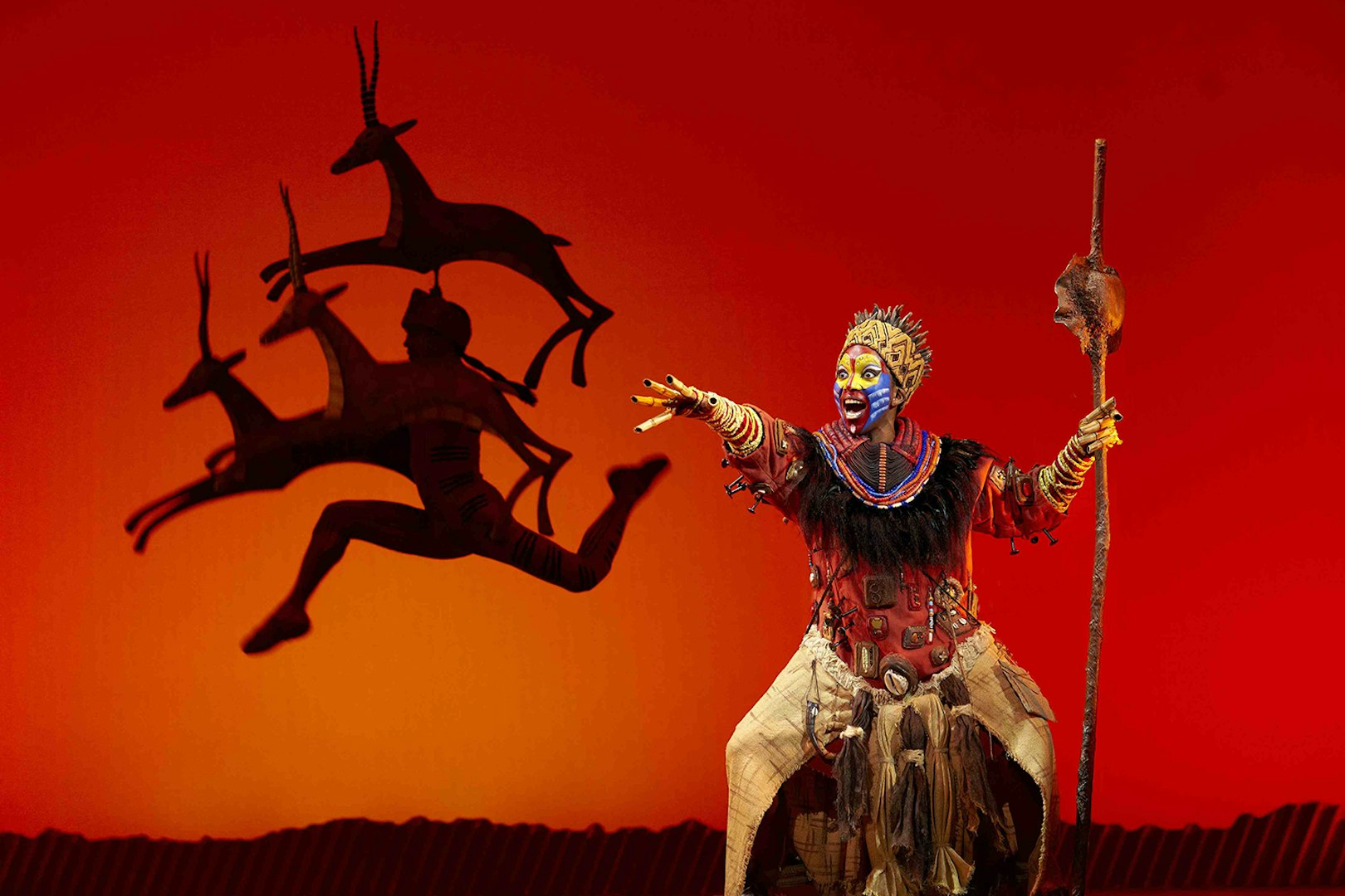 Performer in vibrant costume on stage during The Lion King show in Madrid.