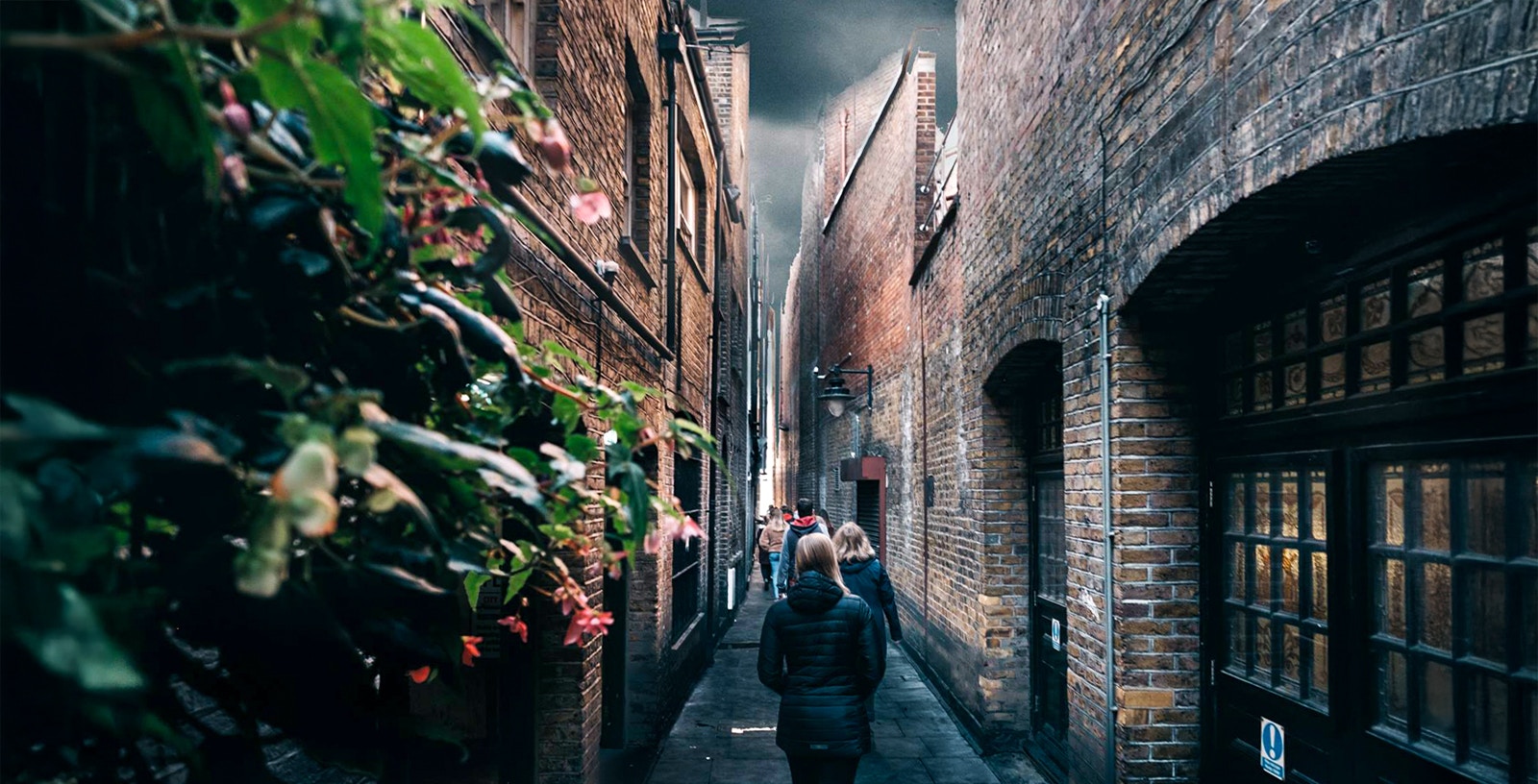 People walking through a narrow alley in London, reminiscent of Harry Potter's Diagon Alley.