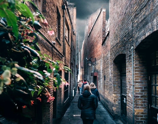 People walking through a narrow alley in London, reminiscent of Harry Potter's Diagon Alley.