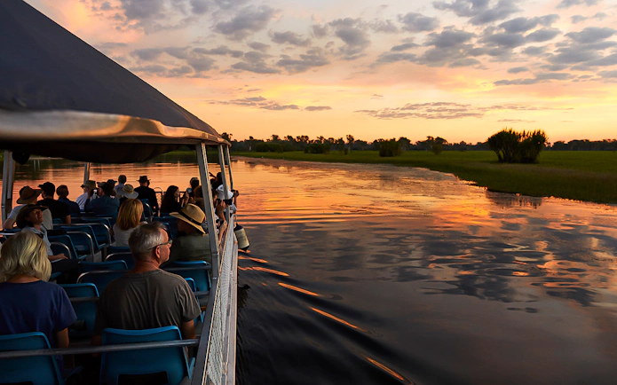Tourists on a boat cruise at sunset in Kakadu National Park's Yellow Water Billabong.