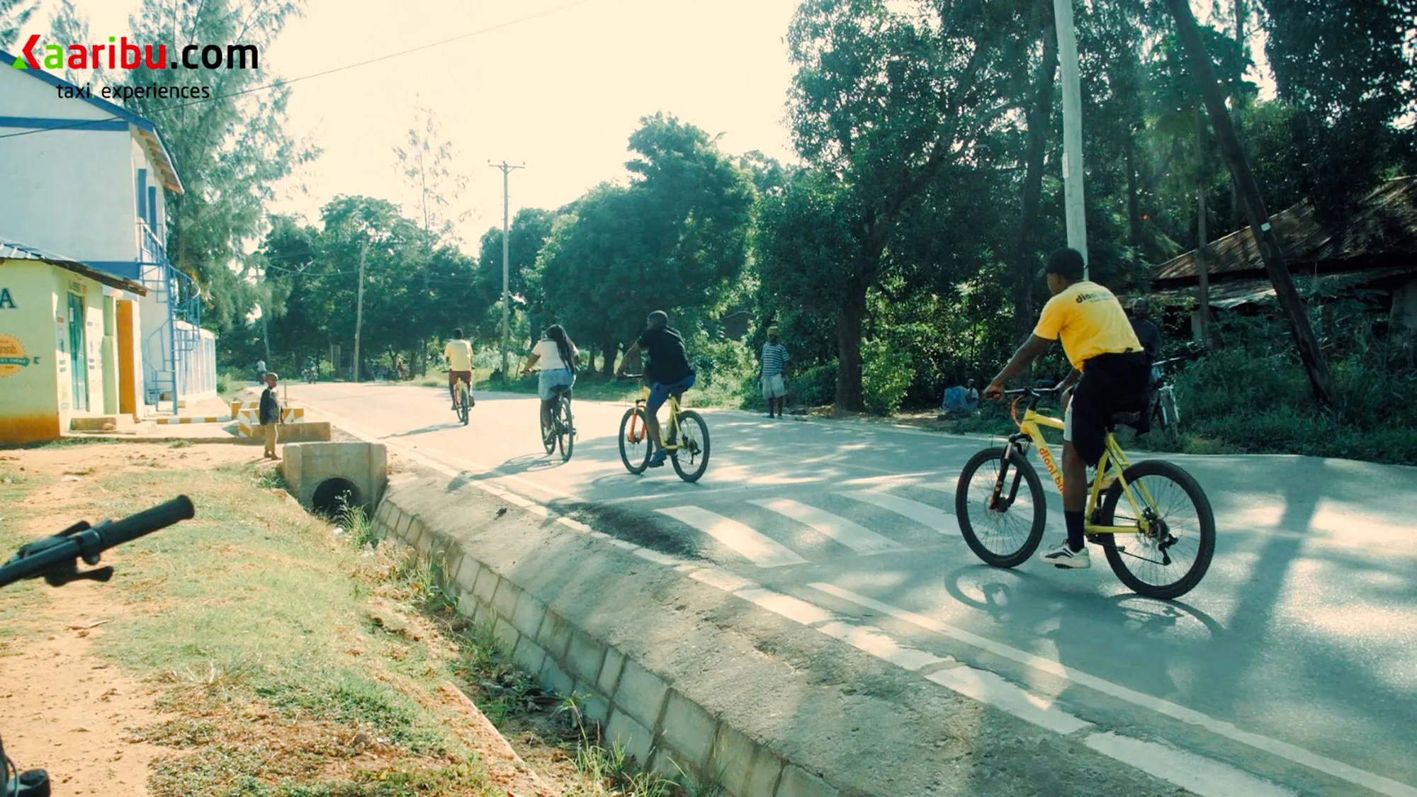 Cyclists on a village road during a bike tour, Diani Beach.