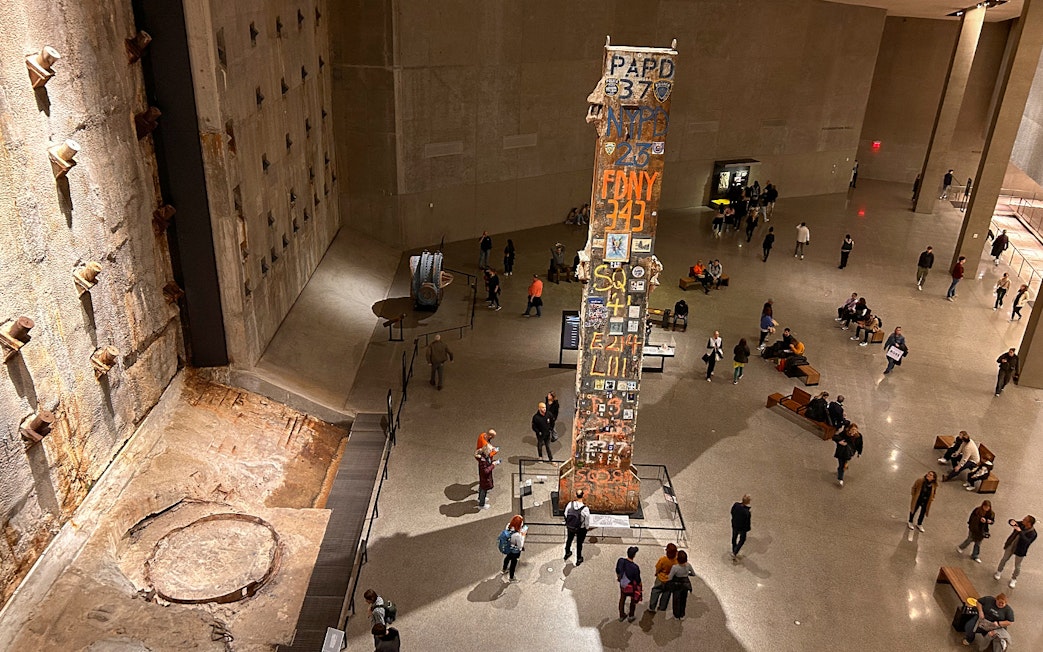 Visitors at the American Museum of Natural History viewing a tall artifact with inscriptions.