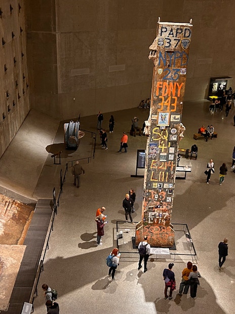 Visitors at the American Museum of Natural History viewing a tall artifact with inscriptions.