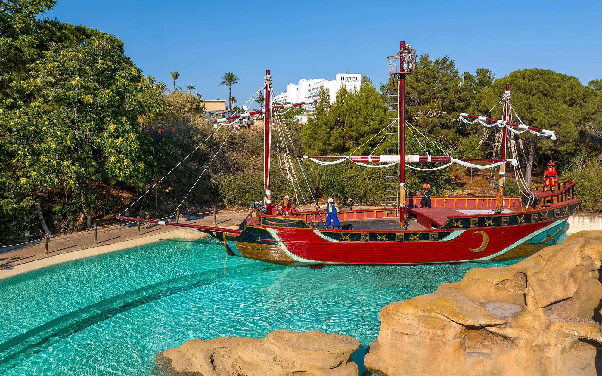 Pirate ship attraction at Terra Mitica theme park, Spain, surrounded by water and trees.