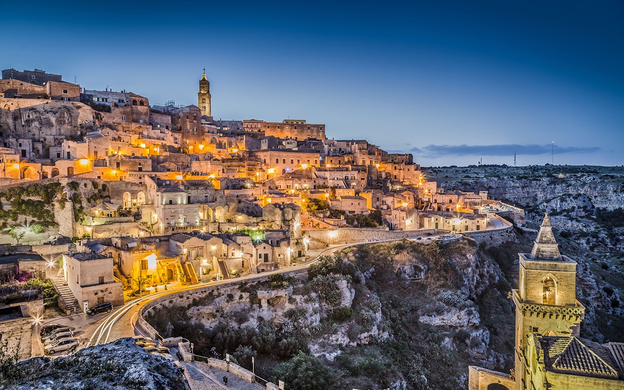 Sassi of Matera illuminated at dusk, showcasing ancient stone buildings and winding streets.
