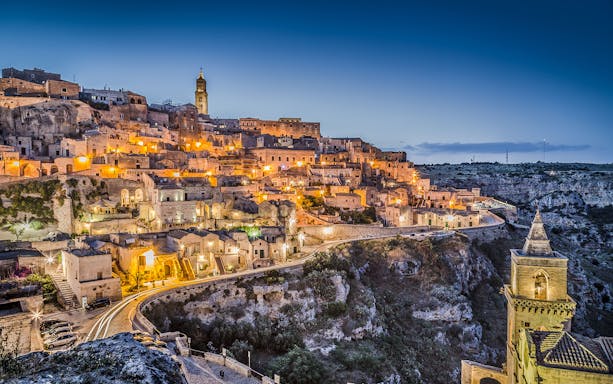 Sassi of Matera illuminated at dusk, showcasing ancient stone buildings and winding streets.