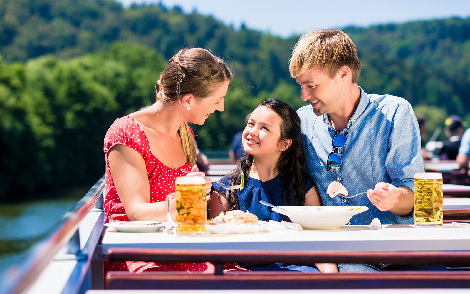 Family enjoying lunch on a Koblenz river cruise with scenic views.